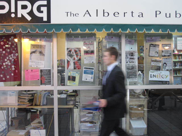 Photo of APIRG window display with person walking in front.