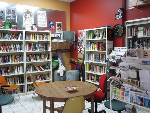 Photo of Office space with bookshelves, table, and multiple pamphlet stands.