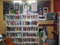 Photo of wall with bookshelves, television, and posters.