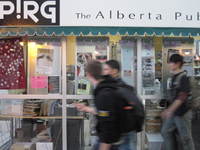 Photo of APIRG store front and window display, with people walking in front. 