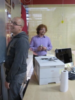 Photo of two men smiling with a office equipment.